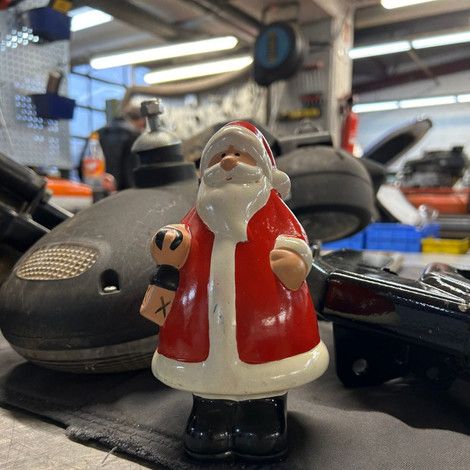 Foto eines kleinen Weihnachtsmannes, im Hintergrund unsere Werkstatt